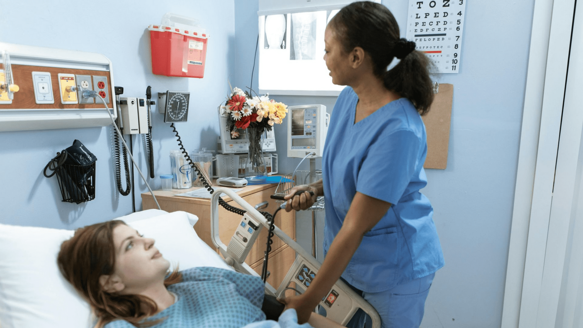 Nurse adjusting medical equipment for a patient in a hospital room.